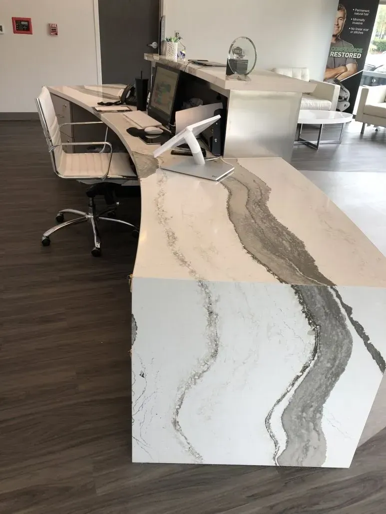 Reception desk with white and gray marble-like countertop in a modern office.