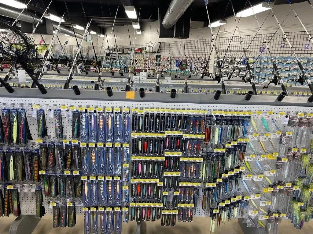Fishing lures and rods displayed on a store wall. Various colors and styles are visible.