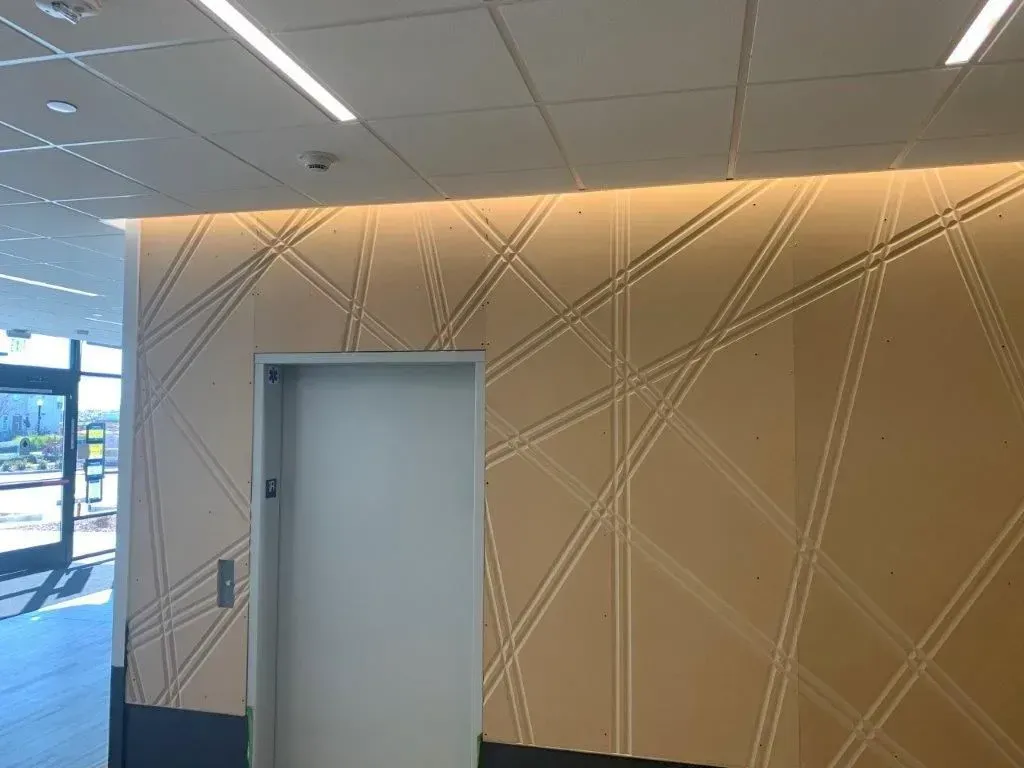 Beige textured wall with white door, geometric design, recessed lighting.