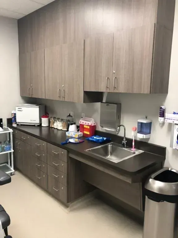 A medical examination room with cabinets, sink, and sterilization equipment. Accessible sink with space underneath.