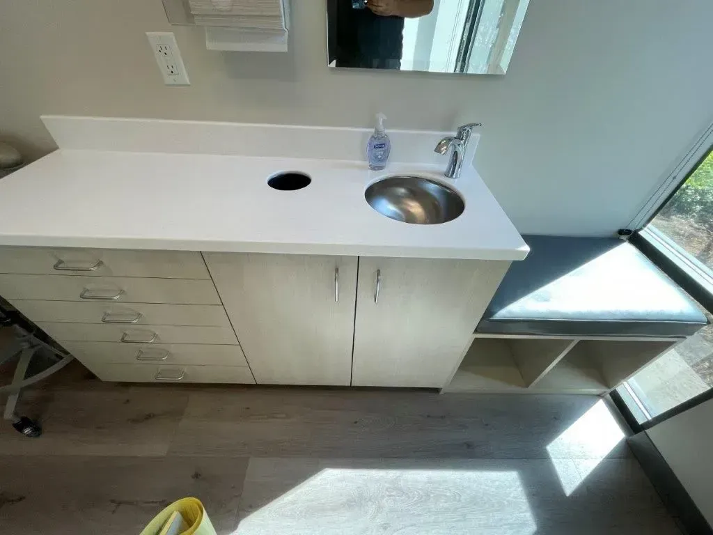 Bathroom vanity with sink, drawers, cabinets, and a built-in bench.