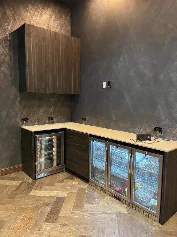 Modern wet bar with dark wood cabinetry, a corner countertop, and built-in coolers.