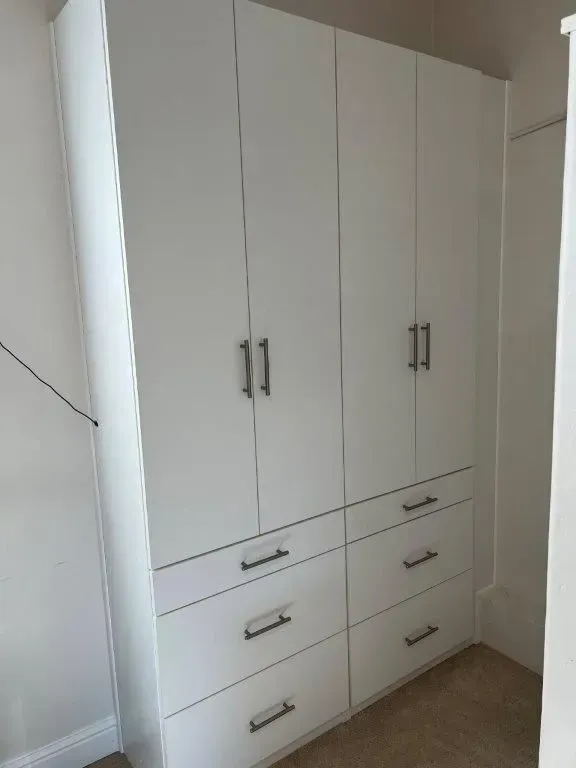 White built-in closet with six doors and six drawers; stainless steel handles.