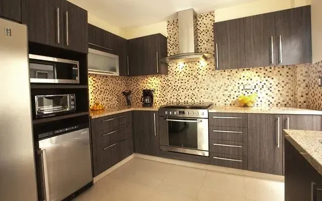 Modern kitchen with dark brown cabinets, stainless steel appliances, and mosaic backsplash.