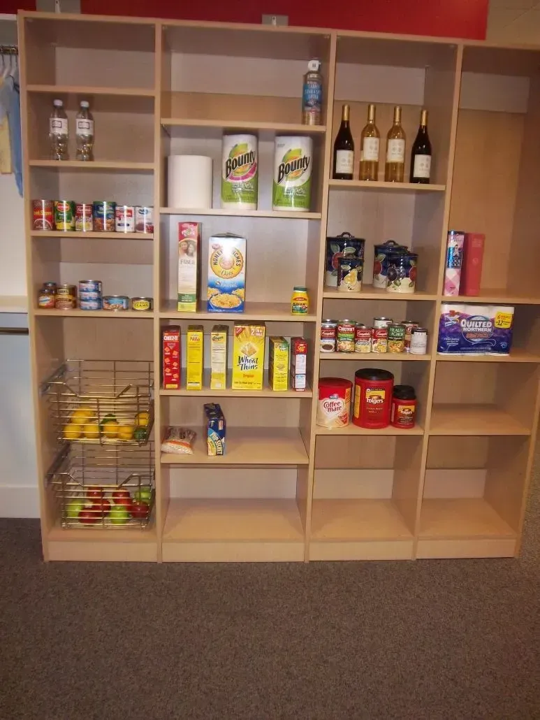 Wooden pantry shelves stocked with various canned goods, cereal, and other food items.