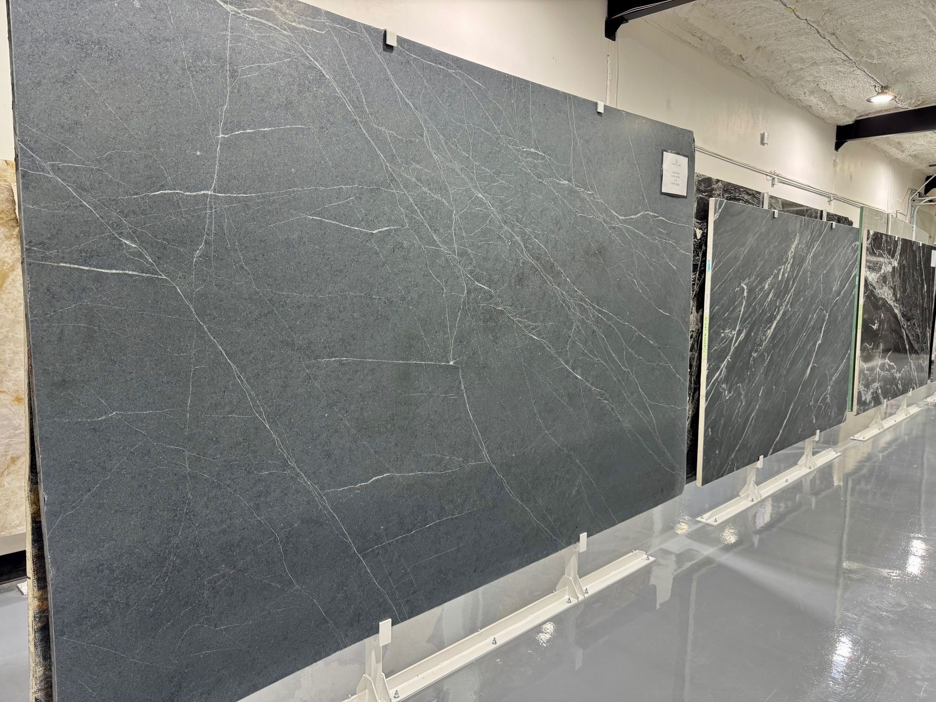A row of black granite slabs hanging on a wall in a room.
