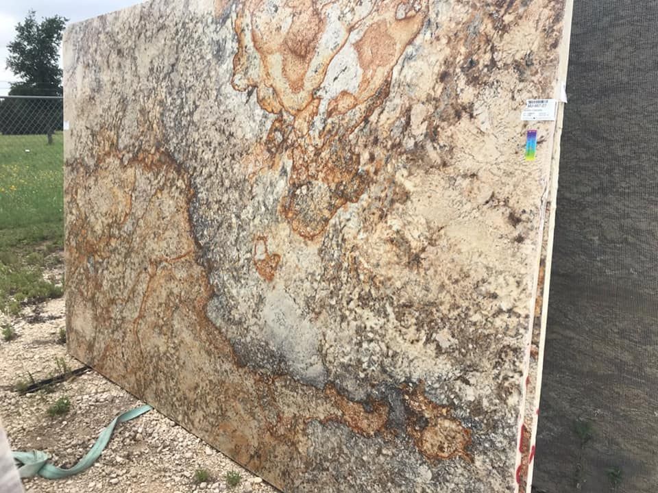 A large slab of granite is sitting on top of a dirt field.