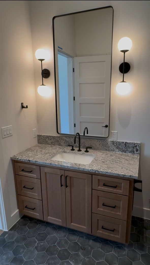 A bathroom with a sink and a large mirror.