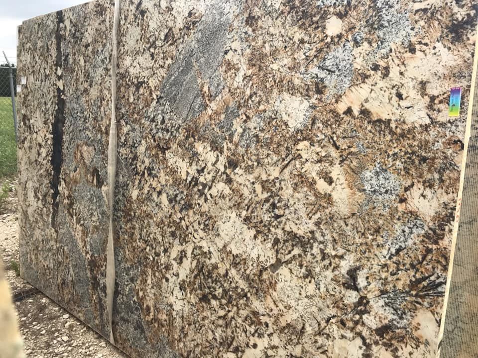 A large slab of granite is sitting on top of a dirt field.