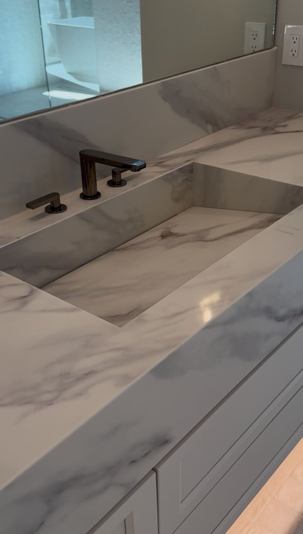 A bathroom sink with a marble counter top and a mirror.