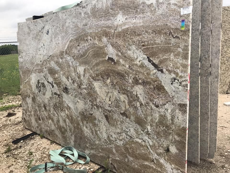 A large slab of granite is sitting on top of a dirt field.