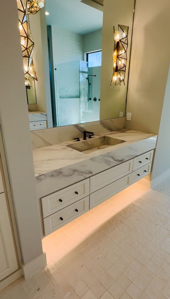 A bathroom with a sink , mirror and drawers.