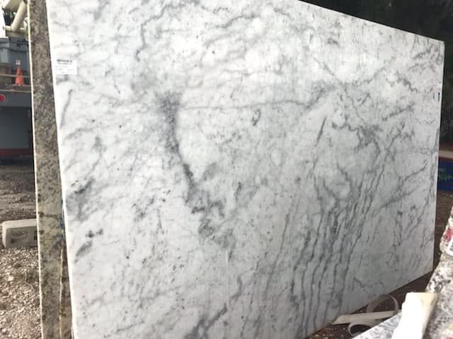 A large white marble slab is sitting on the ground.