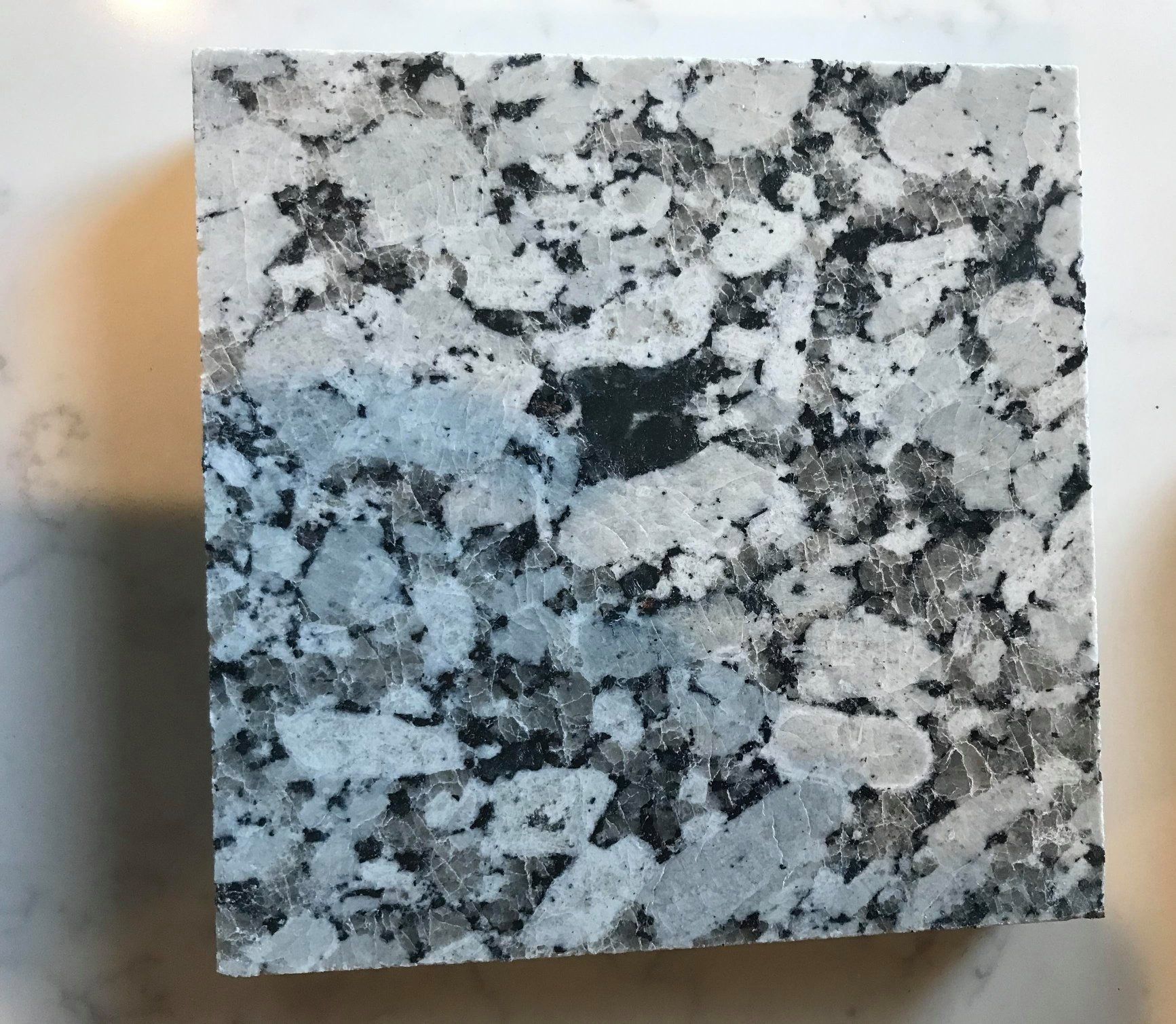 A square piece of granite with black and white spots