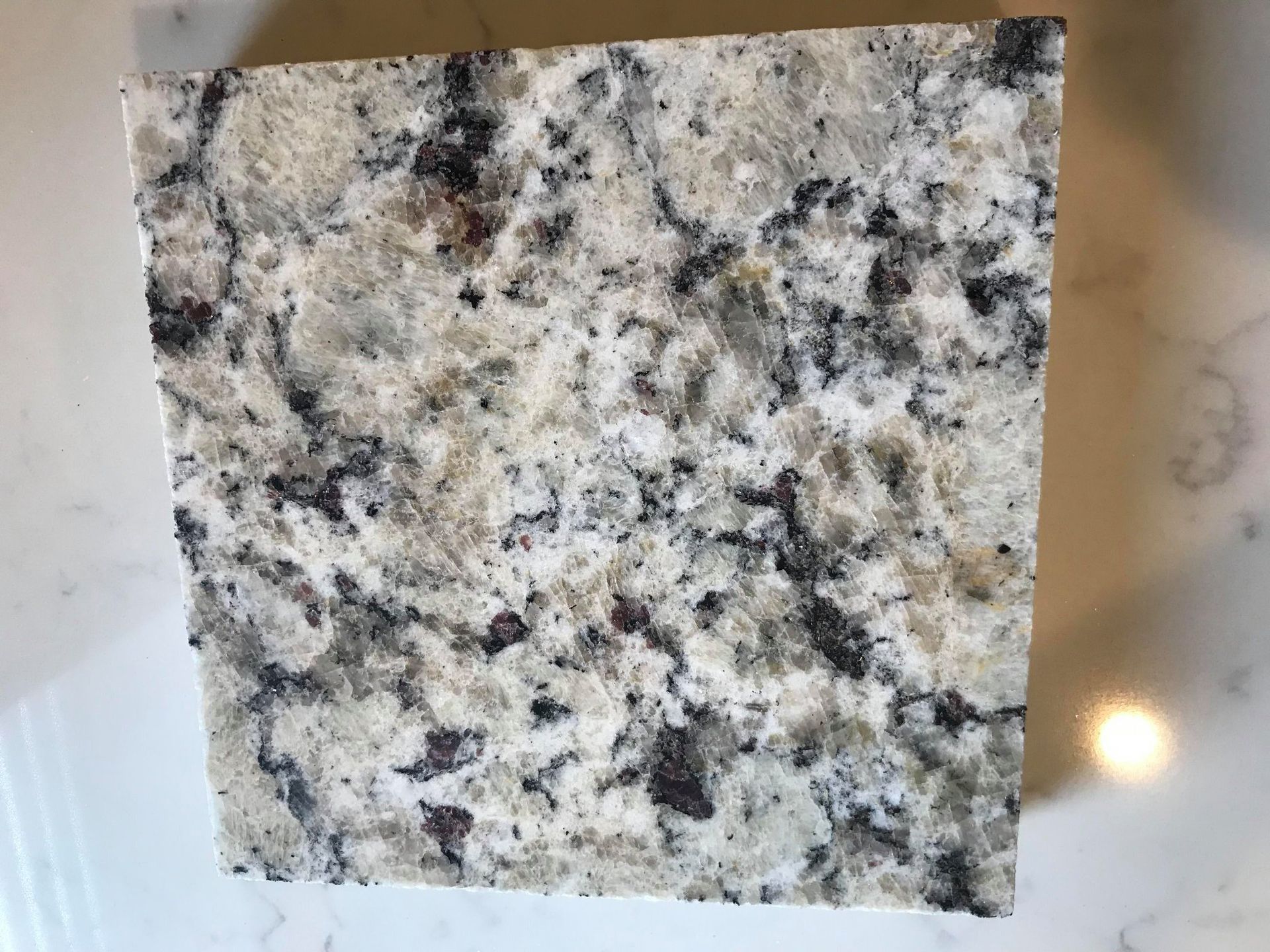 A square piece of granite is sitting on top of a white counter.