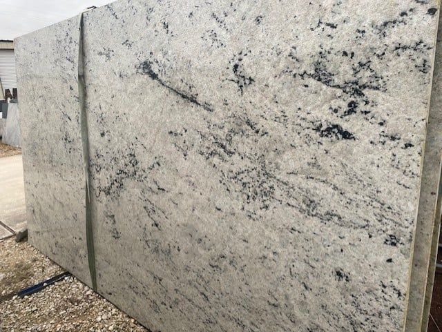 A white granite slab is sitting on top of a pile of gravel.