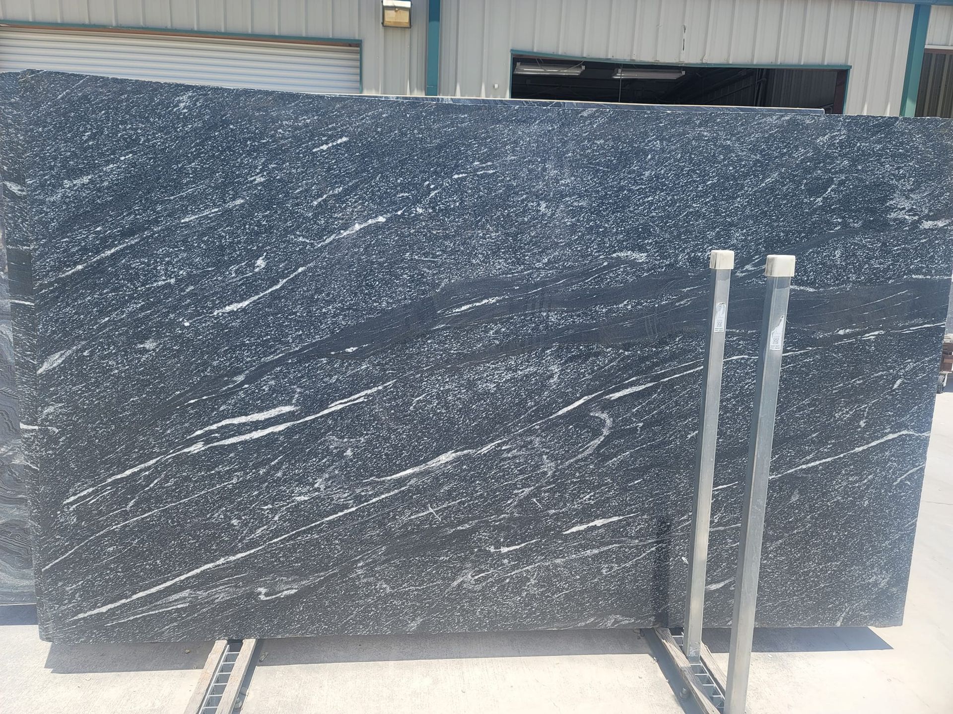 A black granite slab is sitting on a metal stand in front of a building.