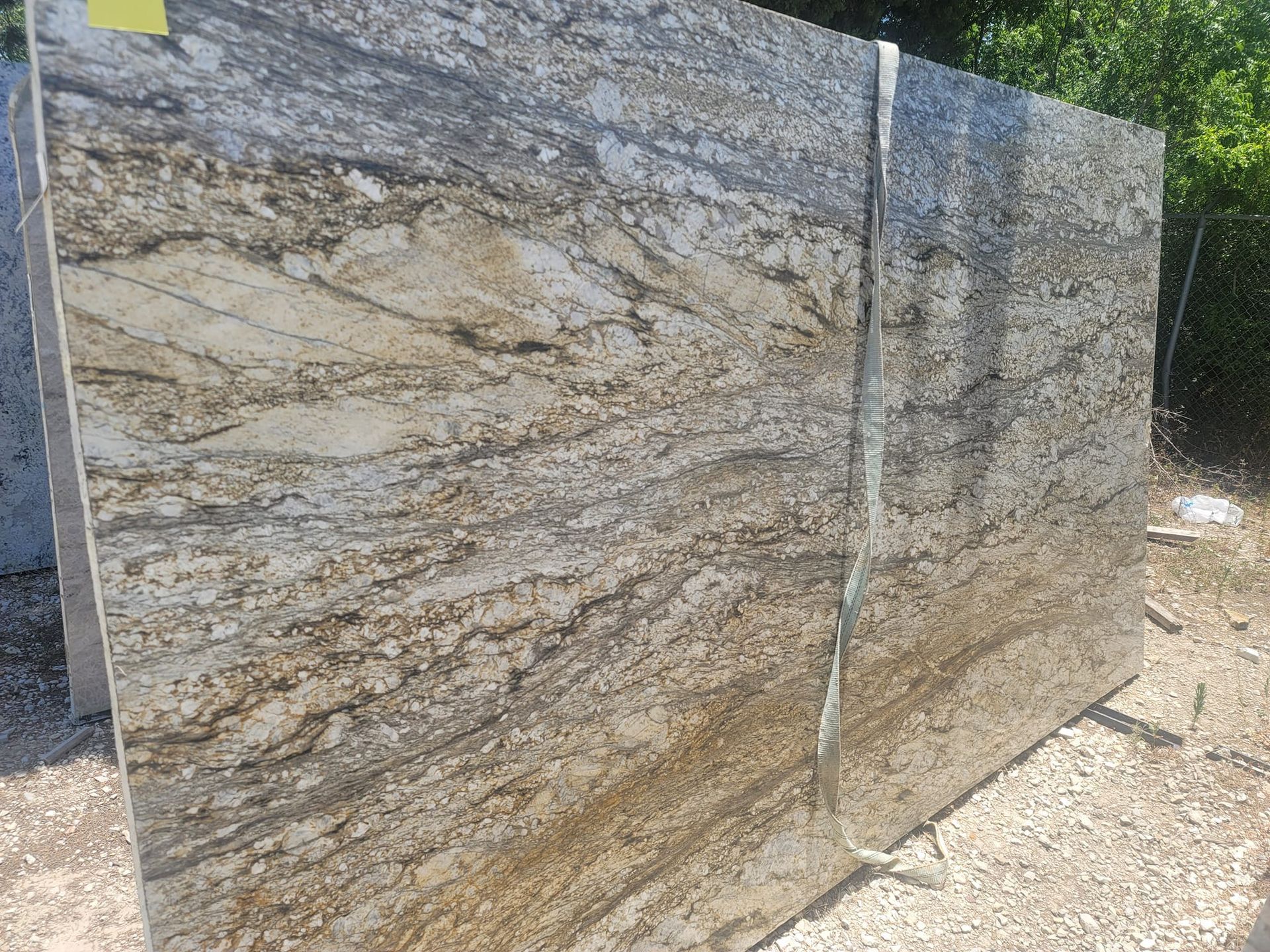 A large slab of granite is sitting on top of a gravel road.