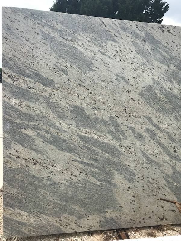 A large slab of granite is sitting on top of a pile of wood.