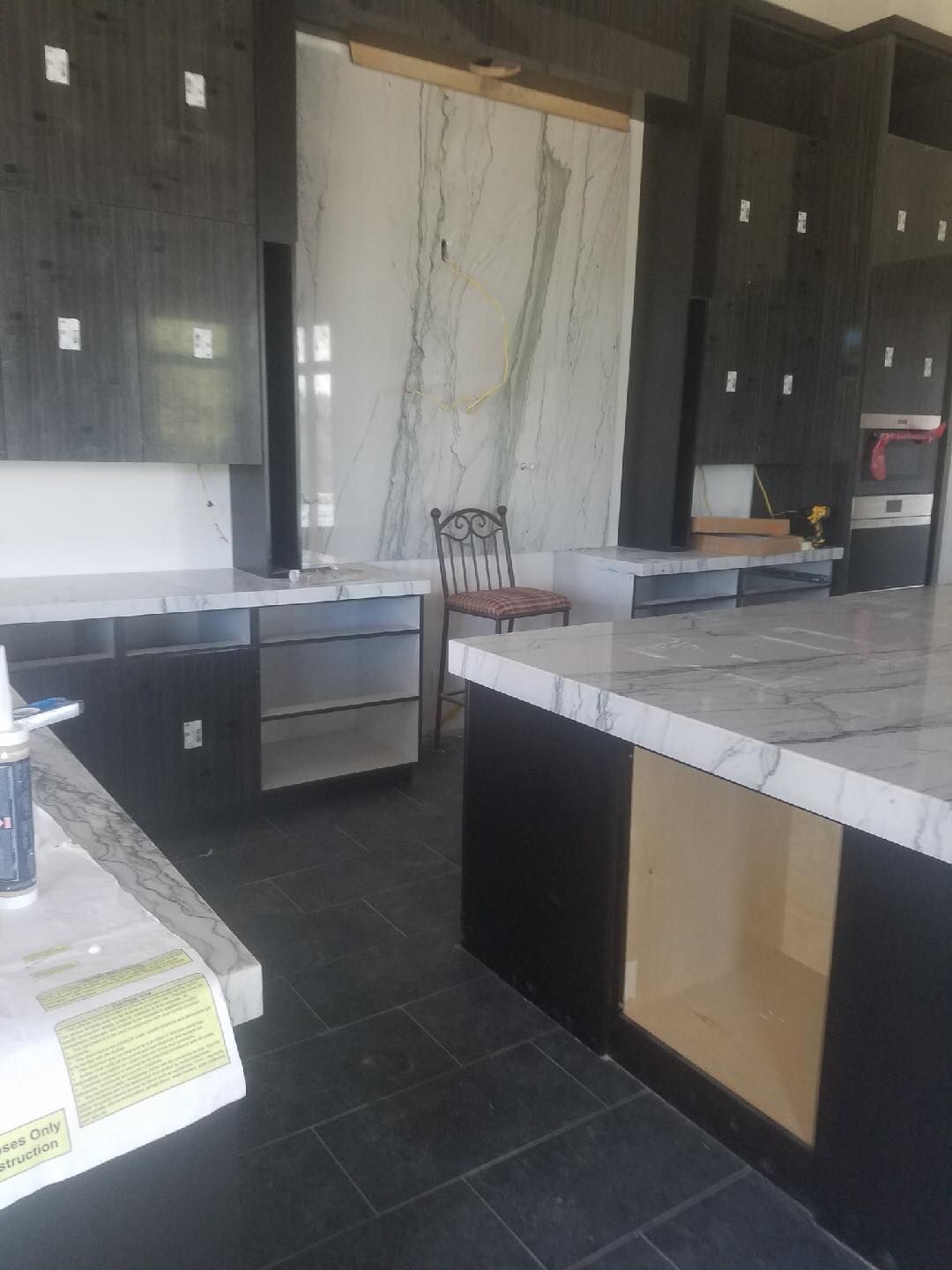 A kitchen with marble counter tops and black cabinets