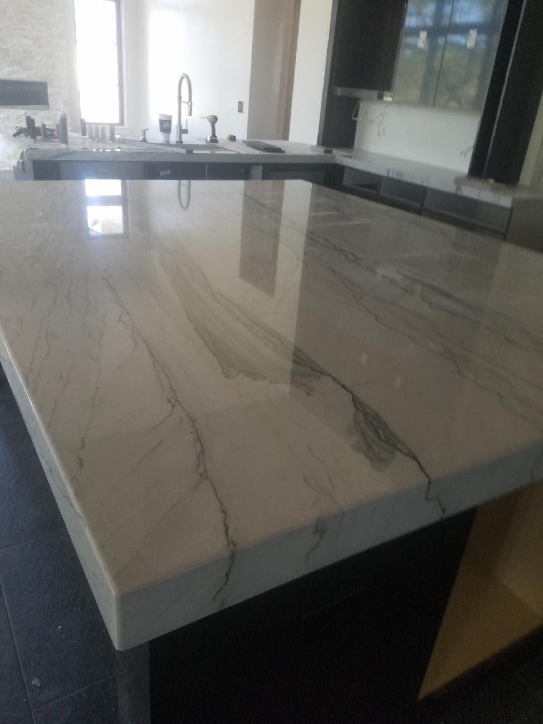 A kitchen with a marble counter top and a sink.