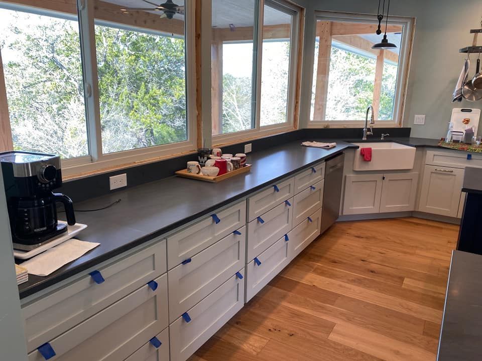 A kitchen with white cabinets and a black counter top.