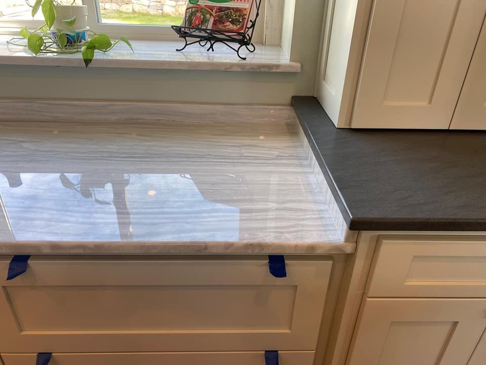 A kitchen counter with a marble counter top and white cabinets.
