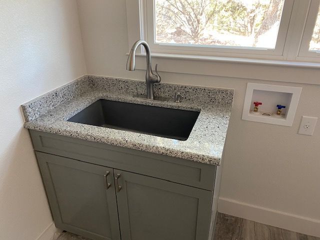A laundry room with a sink and a window.