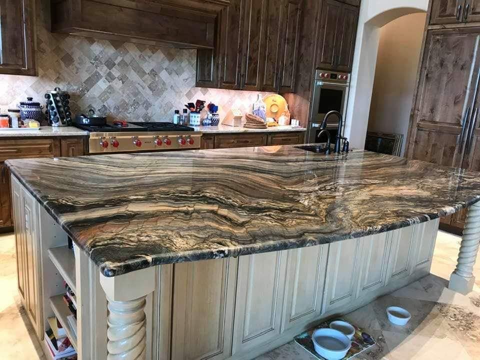 A kitchen with a large granite counter top and two bowls on the floor.