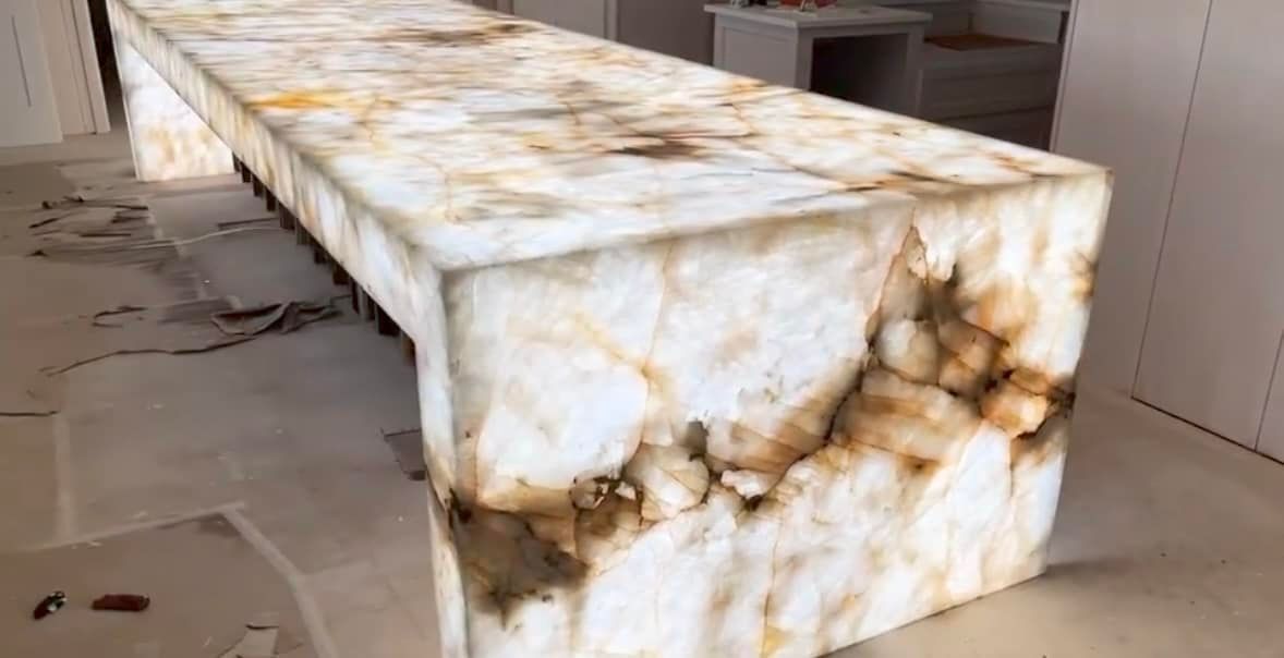 A long white marble counter top is sitting on top of a white floor.