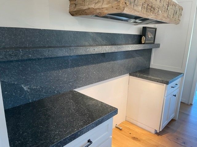 A kitchen with black granite counter tops and white cabinets