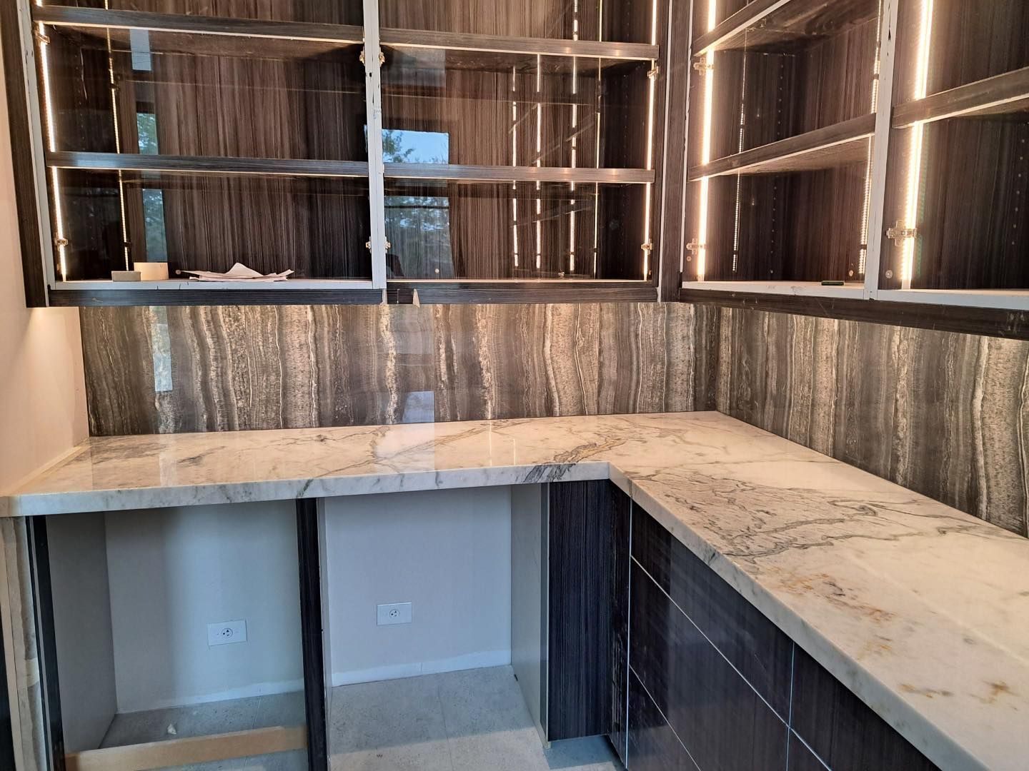 A kitchen with a marble counter top and wooden cabinets.