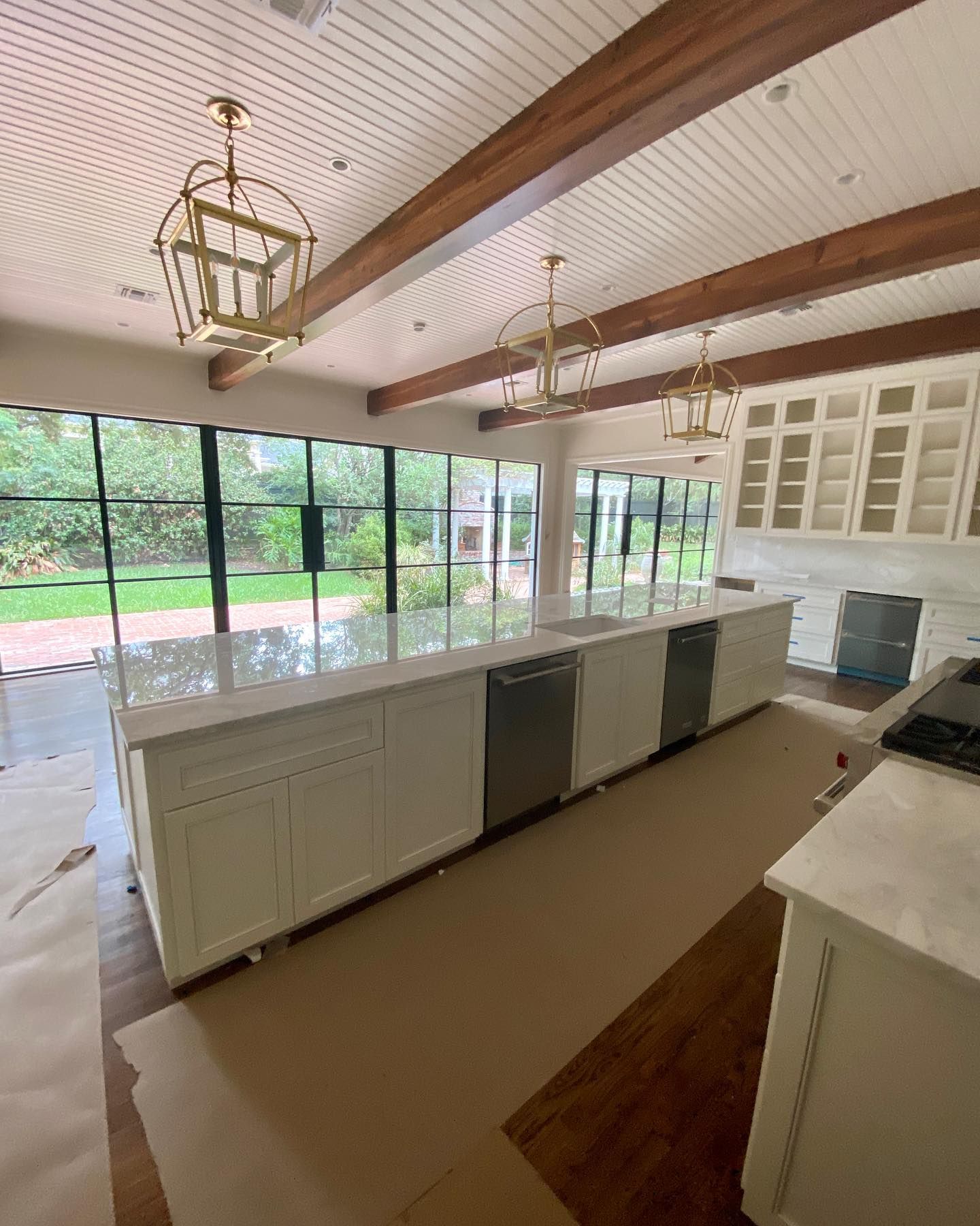 A kitchen with white cabinets , stainless steel appliances , and a large island.