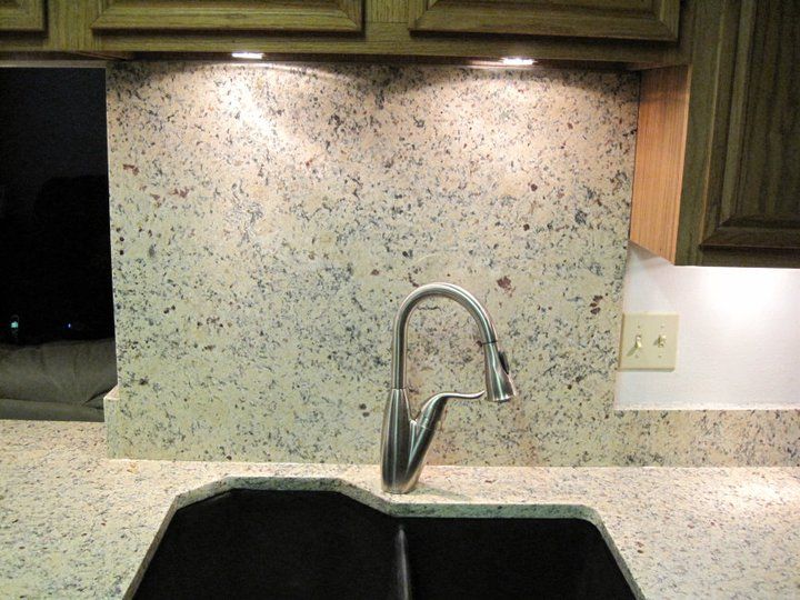 A kitchen sink with a granite counter top and a faucet
