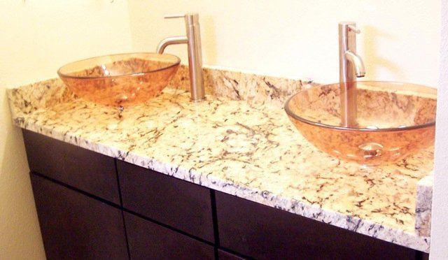 A bathroom with two sinks on a granite counter top.