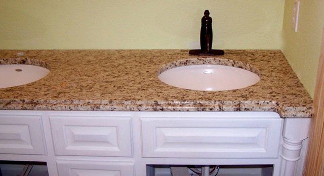 A bathroom vanity with two sinks and a faucet.