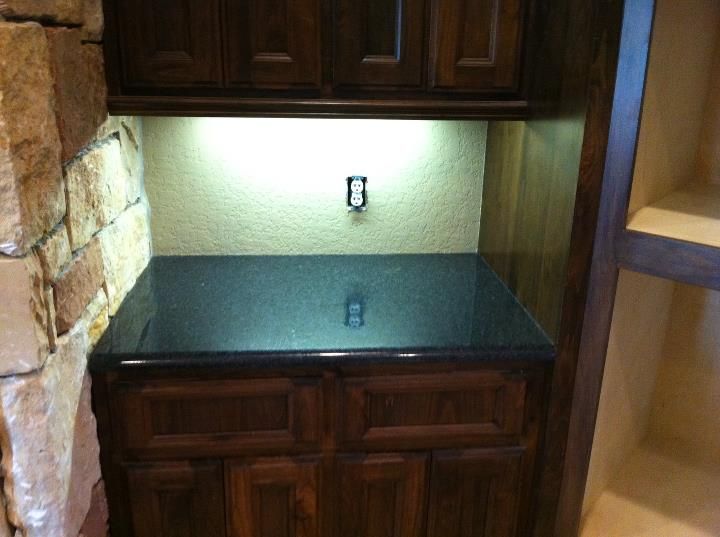 A kitchen with a black counter top and wooden cabinets