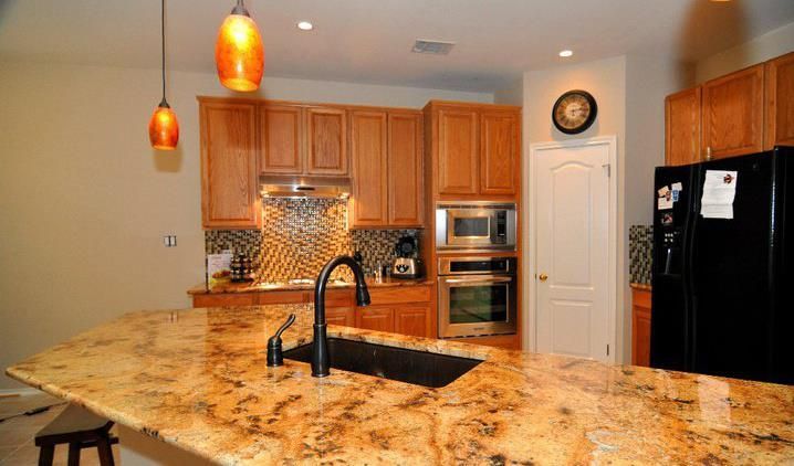 A kitchen with granite counter tops and a black refrigerator