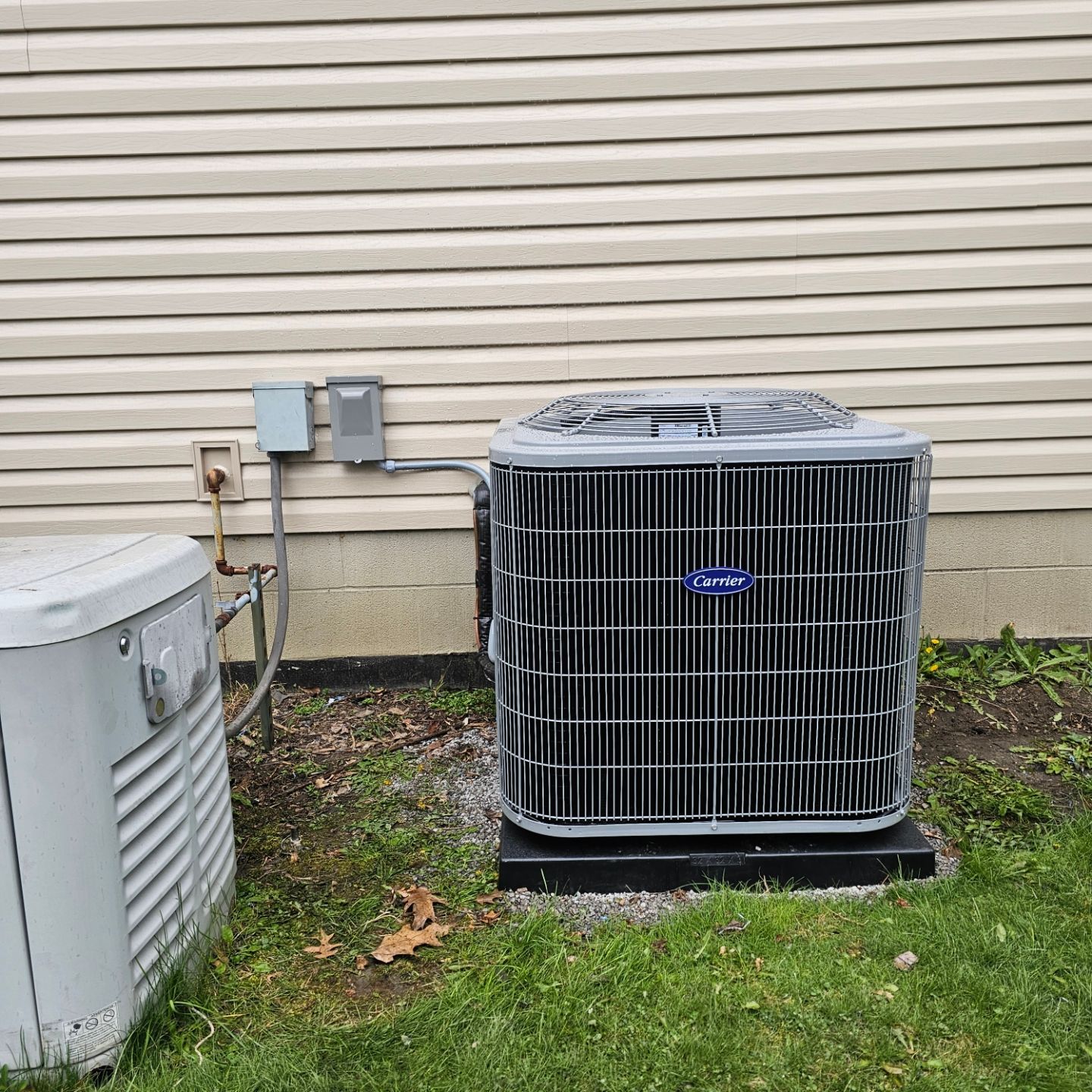 A carrier air conditioner is sitting outside of a house.
