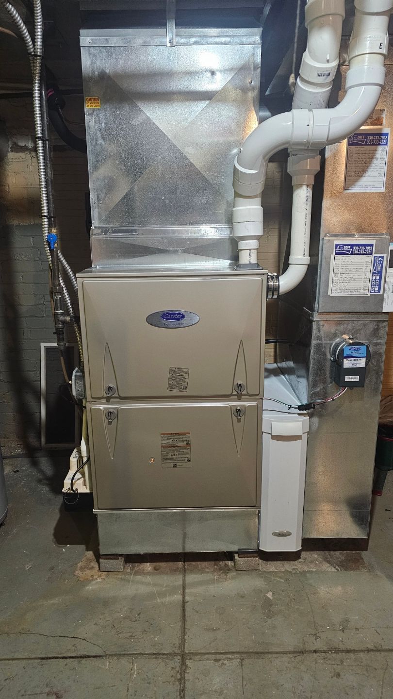 A stainless steel furnace is sitting in the basement of a house.