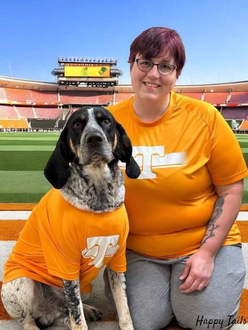 A woman kneeling next to a dog wearing matching t shirts