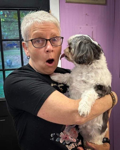 A woman is holding a small dog in her arms.