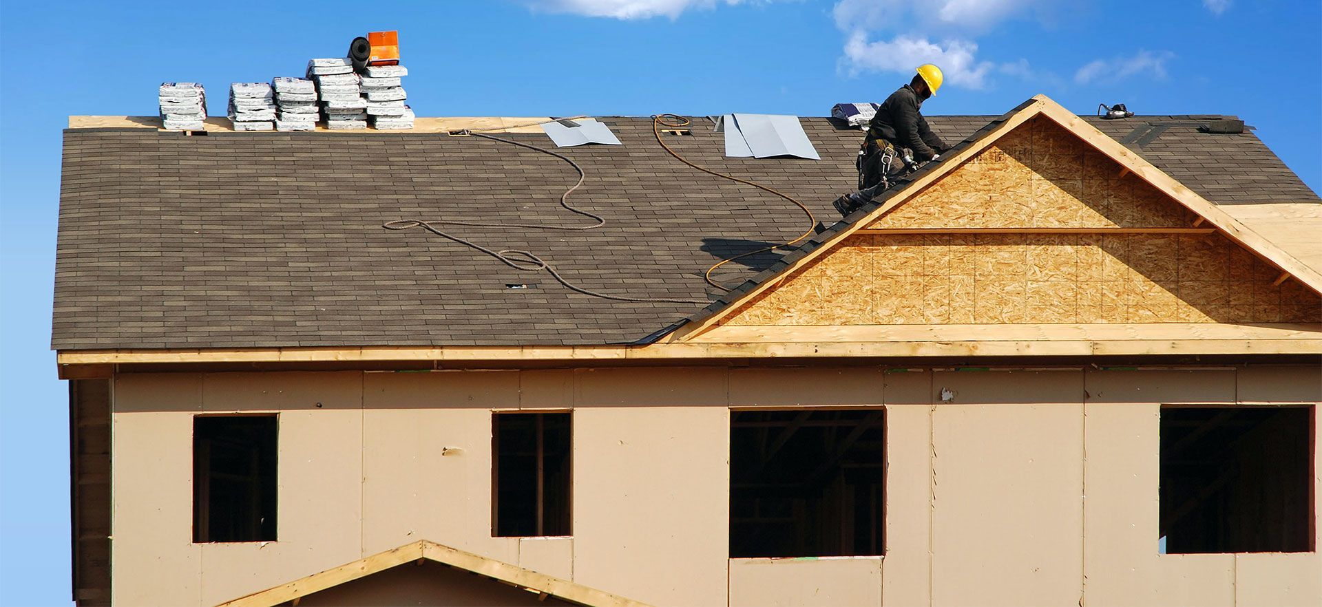 A man is working on the roof of a house under construction