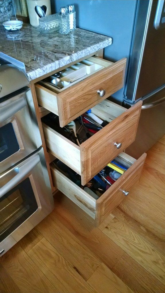 A kitchen with stainless steel appliances and wooden drawers.