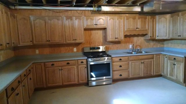 A kitchen with wooden cabinets , a stove and a sink.