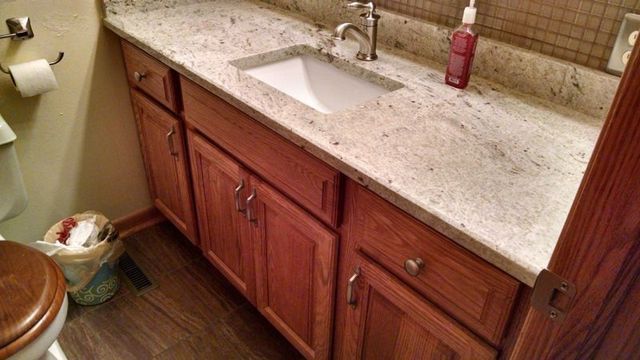 A bathroom with a sink , cabinets , and a toilet.