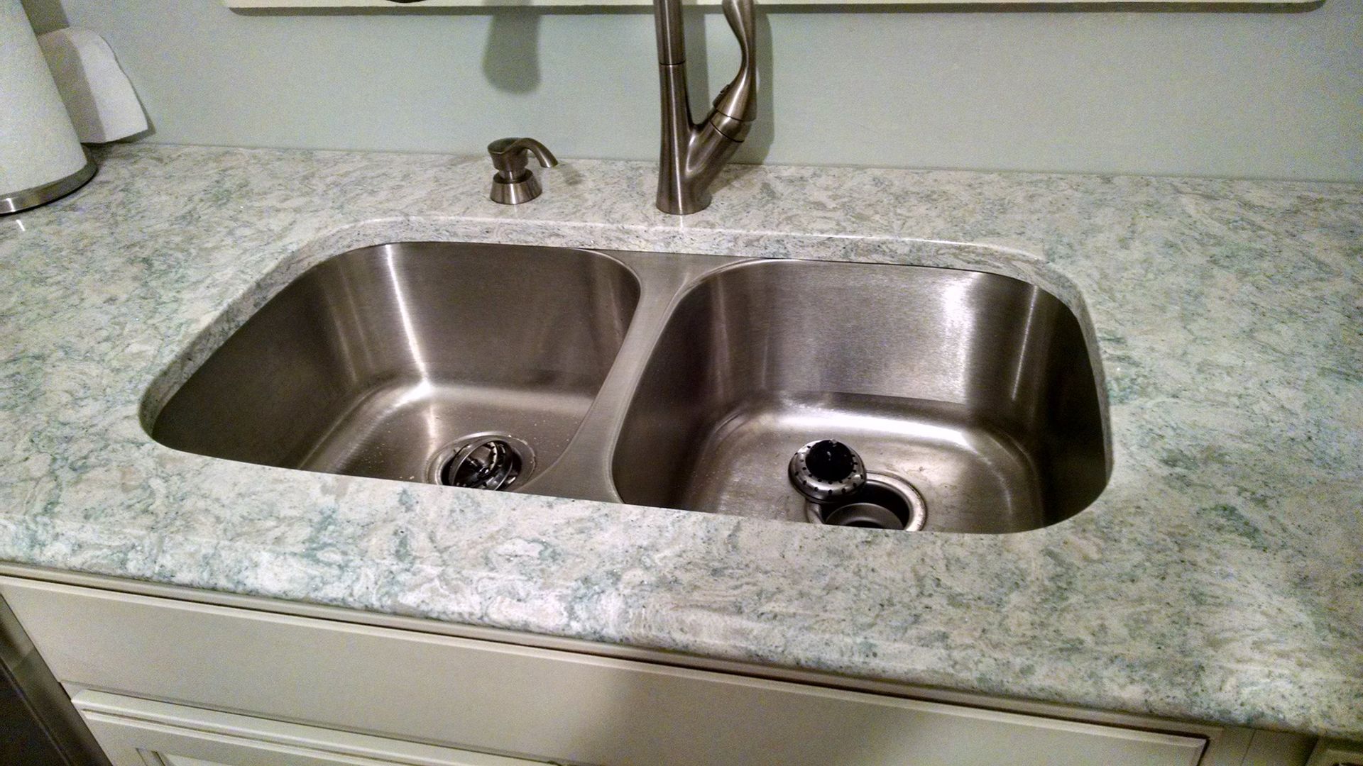 A stainless steel kitchen sink with two bowls and a faucet