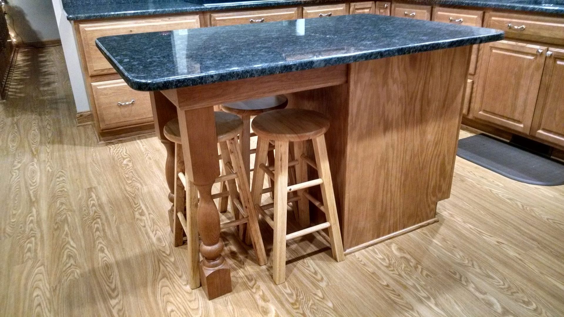 A kitchen island with stools and a granite counter top.