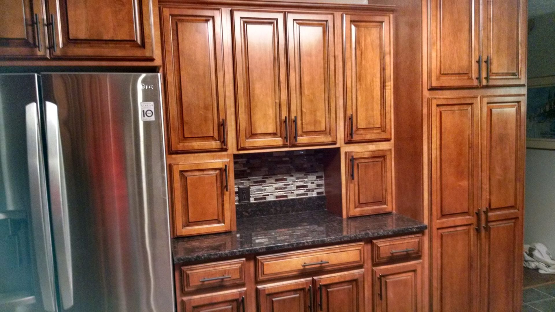 A kitchen with wooden cabinets and a stainless steel refrigerator.