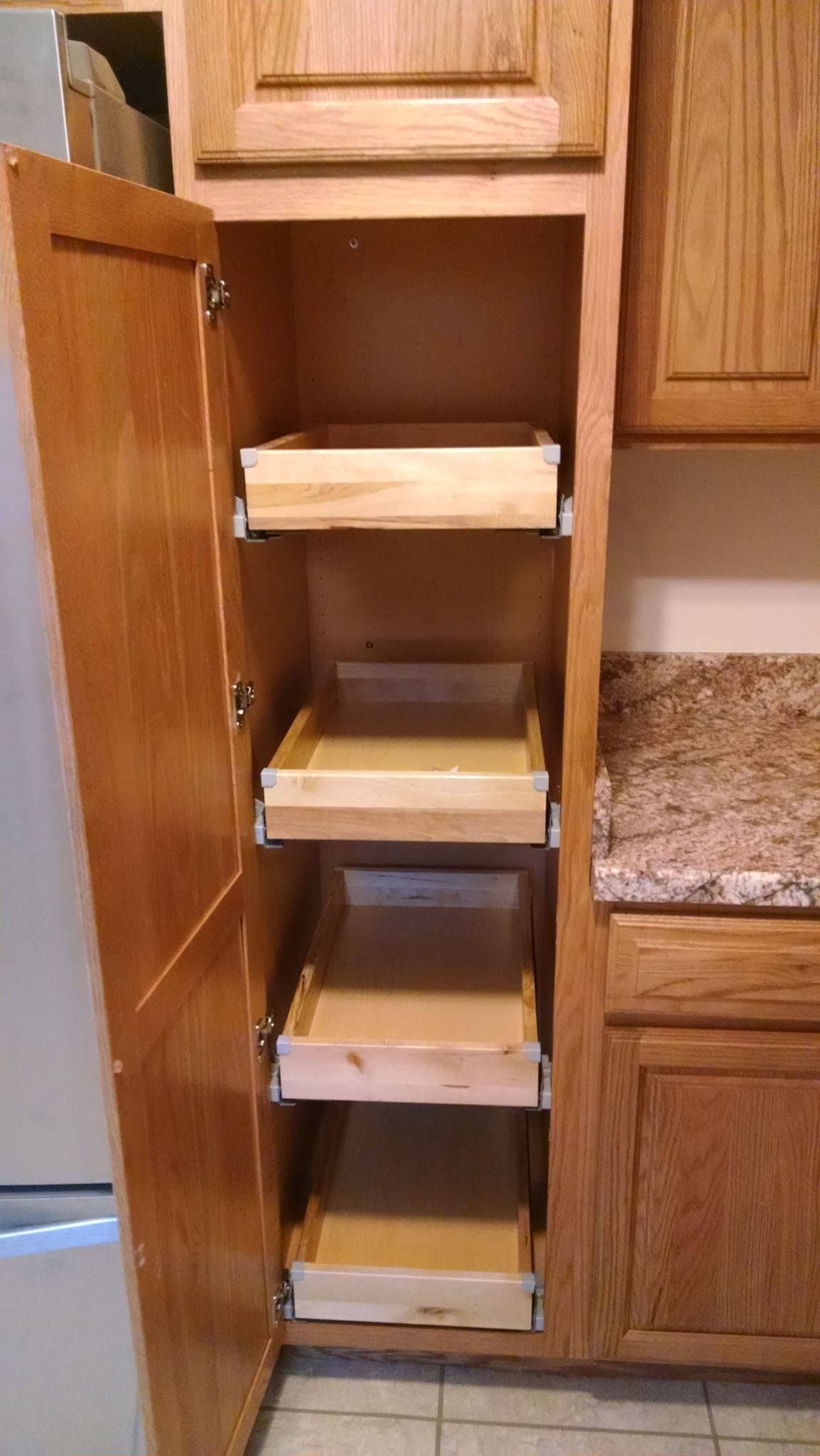 A kitchen with wooden cabinets and drawers and a stainless steel refrigerator.